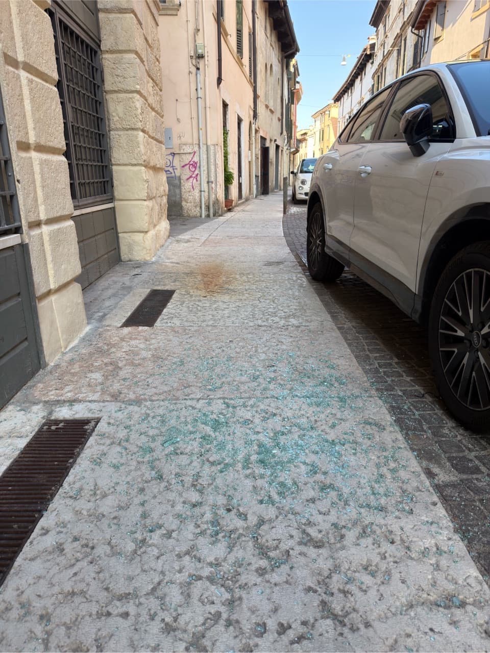 Sono presenti frammenti di vetro sul marciapiede, creando un